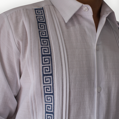 Détail des broderies bleues sur une guayabera blanche élégante