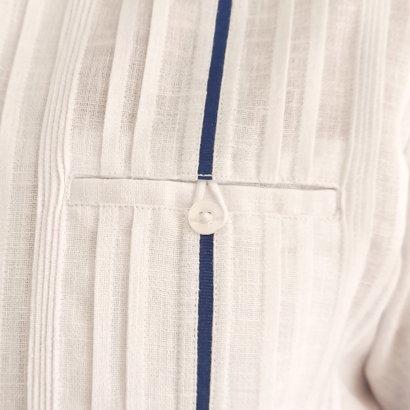 Détail du liseré bleu sur une guayabera blanche élégante en coton