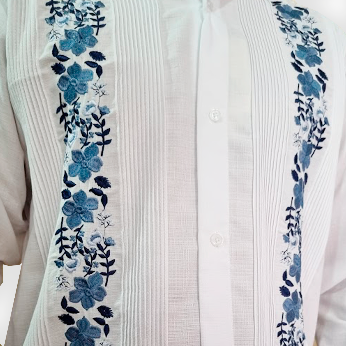 Détail du motif floral bleu sur guayabera blanche élégante artisanale